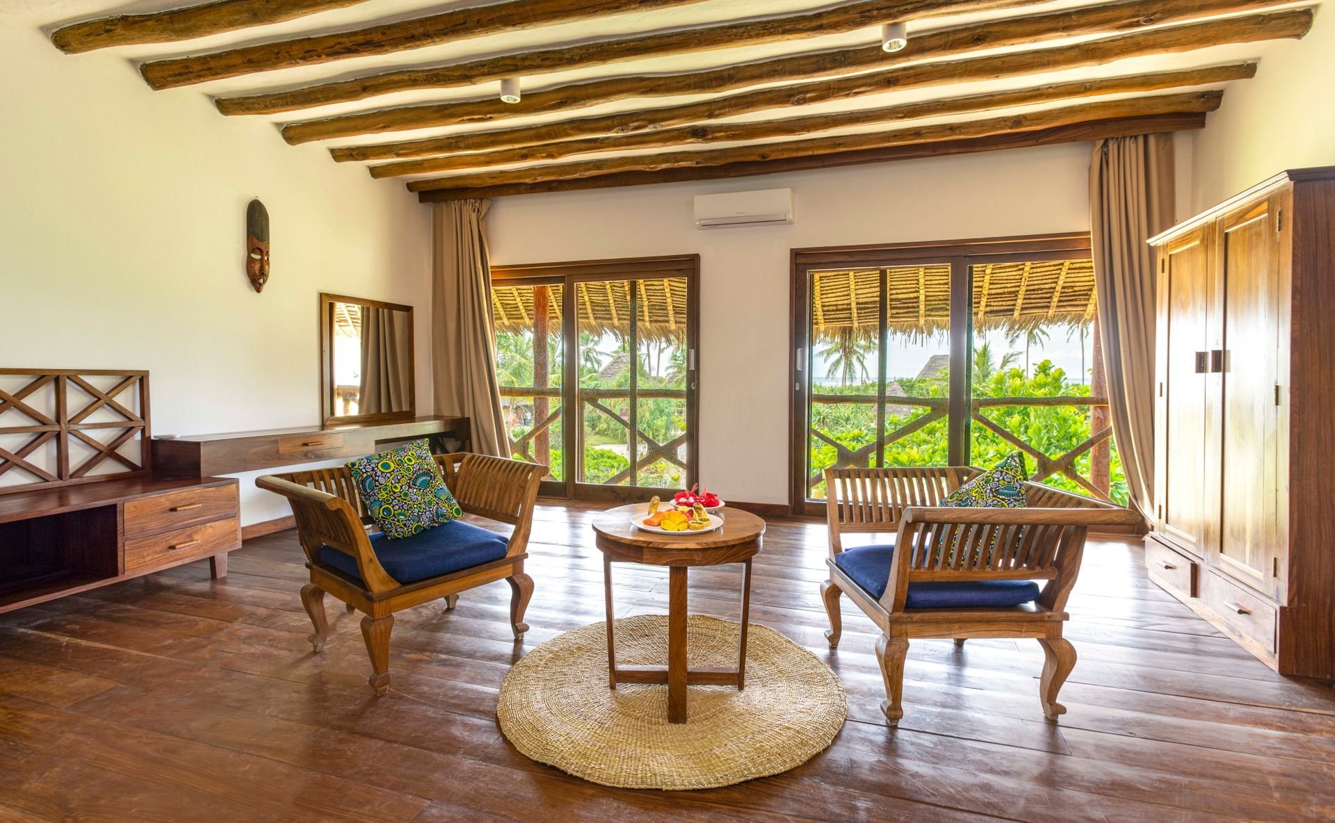 Suite living room with exposed beams and Swahili details, opening to the garden