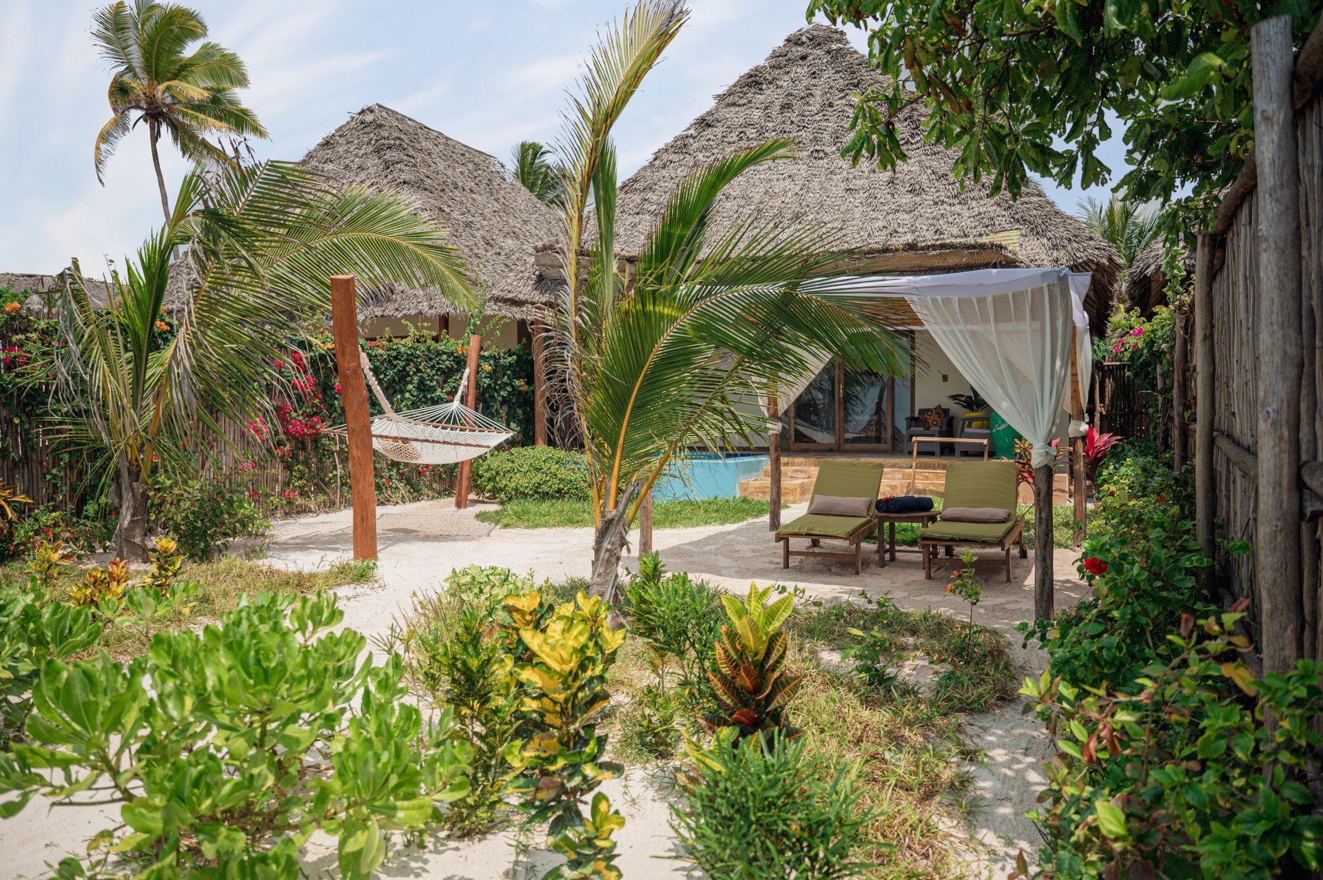Beachfront bungalow garden with a hammock between the palms
